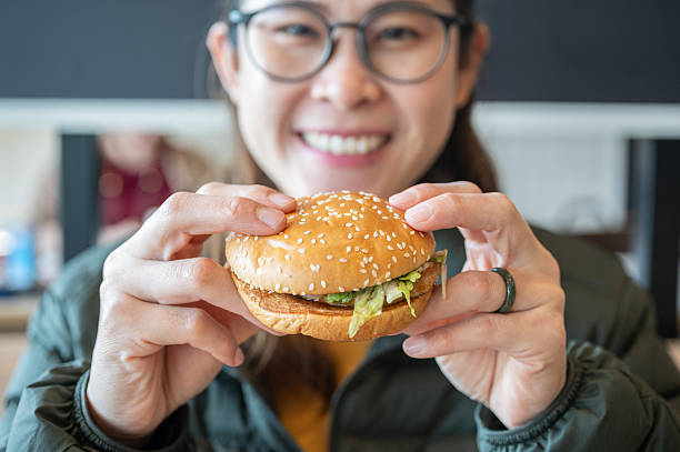 Portrait of young Asian woman holding a hamburger in hand before eating.