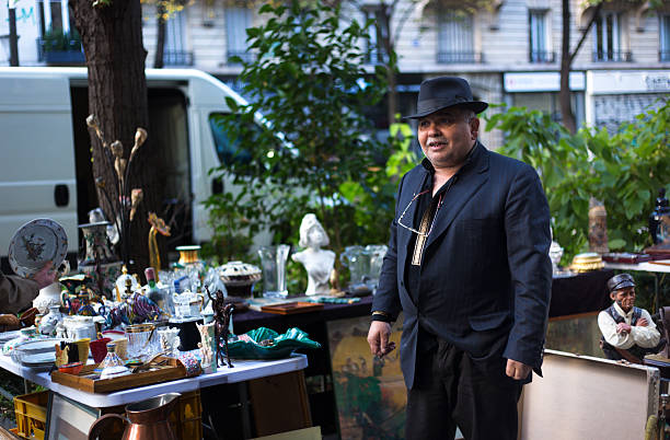 Paris, France - March 25, 2025: An antique dealer/vendor at an outdoor Sunday flea market in the 11th arrondissement.