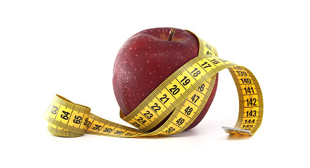 A single red apple is encircled by a yellow tailor's tape measure, symbolizing health and diet