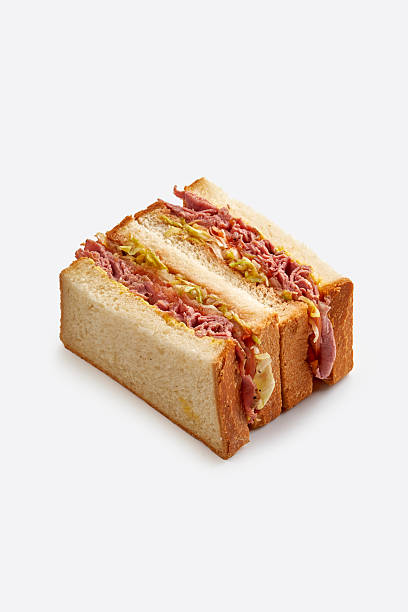 Reuben sandwich or pastrami on rye with thinly sliced meat, cabbage, and dressing, isolated on white background.