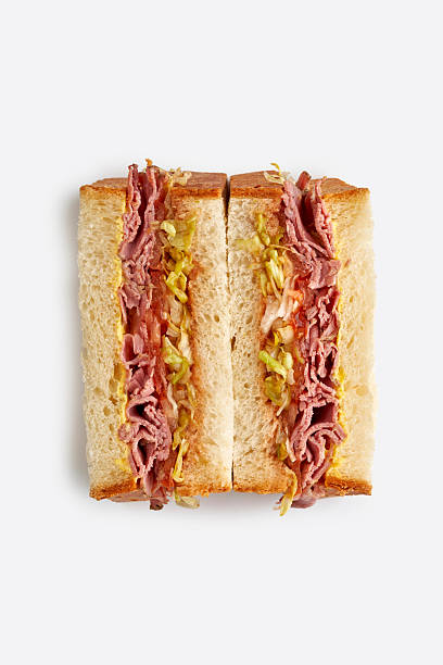 Reuben sandwich or pastrami on rye with thinly sliced meat, cabbage, and dressing, isolated on white background.