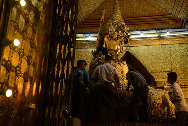 Men only sticking golden leaves over the 4 meter bronze statue of Buddha