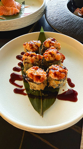 Delicious fried sushi rolls topping with spicy sauce. Taken on mobile device