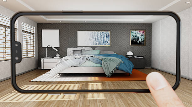 A smartphone shows a virtual modern bedroom with a large bed and colorful blankets. The room has natural light coming through windows. The walls have pictures and the floor is wooden. Artwork on the wall are from my own portfolio.