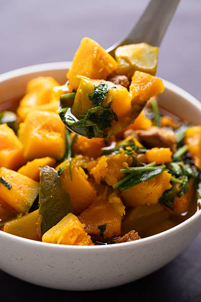 Thai spicy pumpkin curry soup with pork in a bowl scooping by spoon