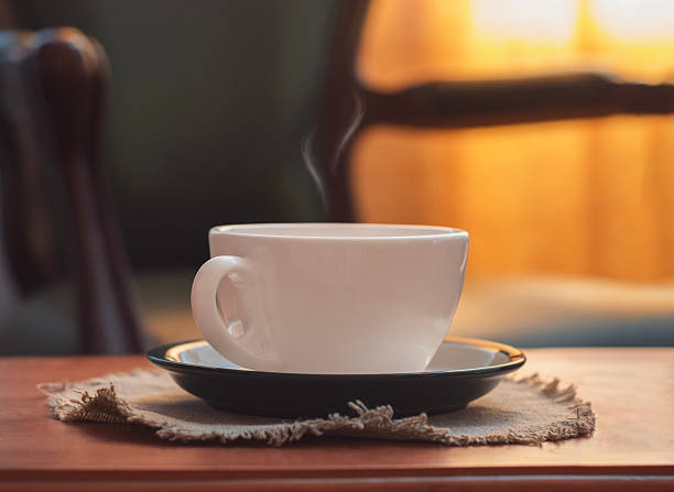 Cozy still life with a steaming cup of hot coffee on a wooden table in warm natural sunlight, creating a calm and peaceful home atmosphere perfect for morning relaxation, comfort, and quiet moments.
