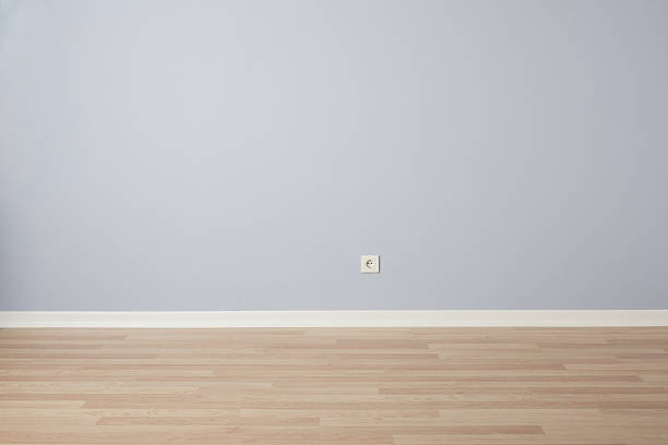 A clean and minimalist interior scene featuring a light blue wall, white baseboard, and natural wooden floor. The empty room provides a simple and versatile backdrop ideal for design mockups, real estate presentations, home renovation concepts, interior design visuals, product placement, advertisements, and editorial use. The neutral colors and uncluttered layout make it perfect for creative projects requiring a calm, modern, and spacious background.