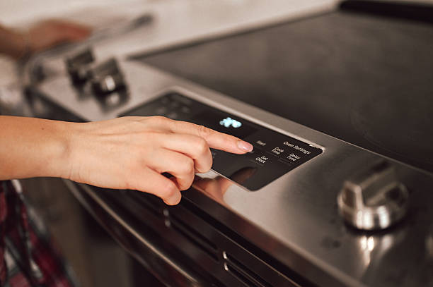 Person hand pressing kitchen oven control panel start button