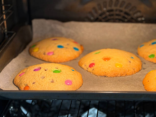Image of creative cooking and baking rainbow chocolate chip cookies / colourful biscuits on tray made from cookie dough