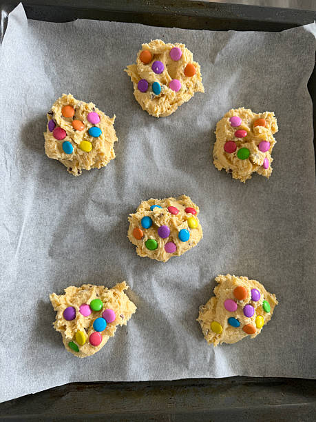 Image of festive making rainbow chocolate chip cookies / colorful biscuits from cookie dough, packed with candy and sweet