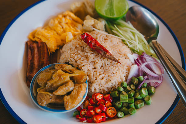 Kao kluk kapi. Fried rice with chili lime sliced onion sliced chili green beans egg spoon fork plate