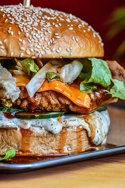 Close-Up Chicken Burger With Melted Cheese, Lettuce And Sesame Seed Bun