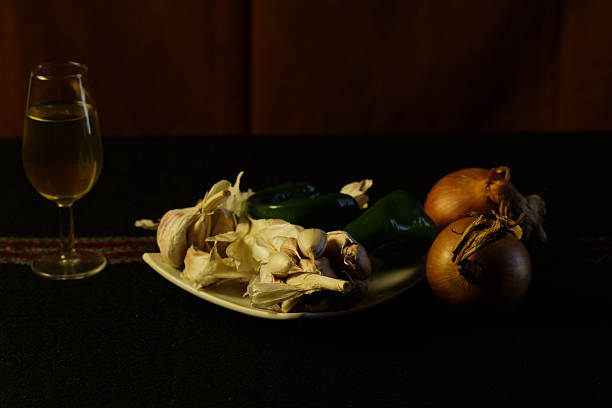 Garlic Onions And Wine Glass Arranged On Ceramic Plate Under Warm Low Light Dark Backdrop, Textured Cloth,