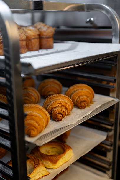 Freshly baked croissants and pastries cooling on bakery rack
