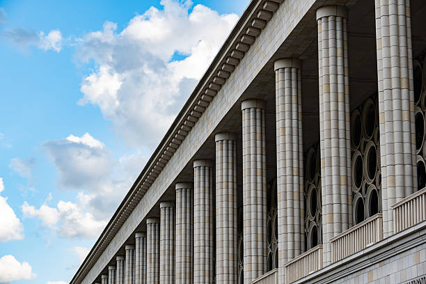 Building facade featuring many classic columns, geometric patterns, and round windows under a bright sky