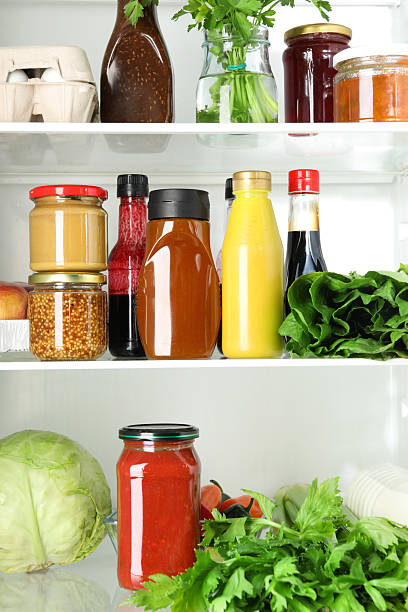 Bottles with different tasty sauces and products in fridge, closeup