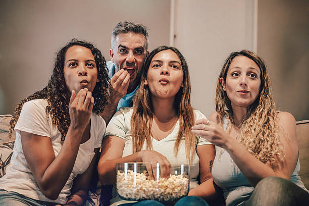 three woman and a man watching tv together