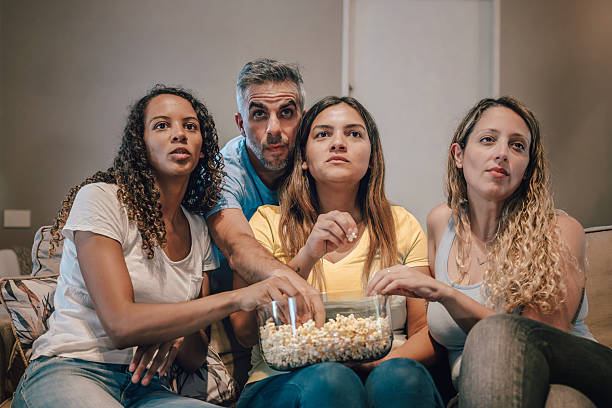 three woman and a man watching tv together