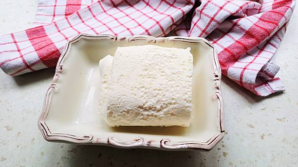 A close-up photograph of fresh cream. Served on a rustic white plate with a red checkered napkin in the background, the creamy white texture of the cream creates an appetizing contrast. This scene represents a healthy and traditional Mediterranean breakfast, perfectly suited for Iftar and Sahur meals. Ideal for food blogs, dairy marketing, and healthy lifestyle content.