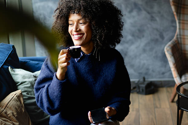 Young beautiful cheerful woman sitting in a cafe and drinking coffee during a break