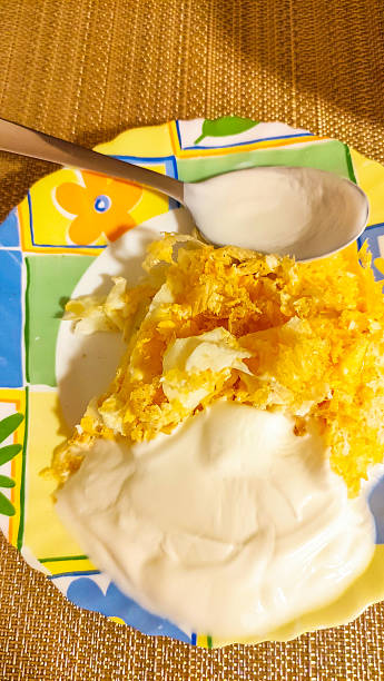 Scrambled eggs with yogurt and spices on colorful plate with spoon