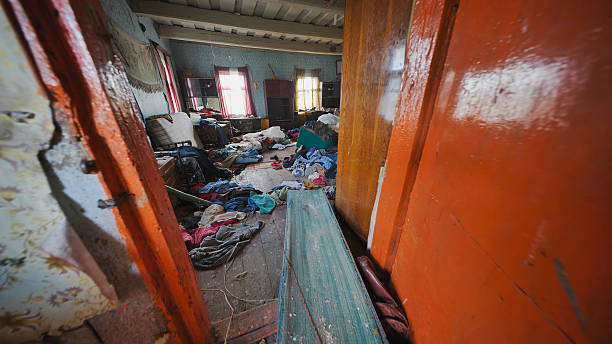 Cluttered, neglected room, floor covered with debris, dirty clothes, and household items