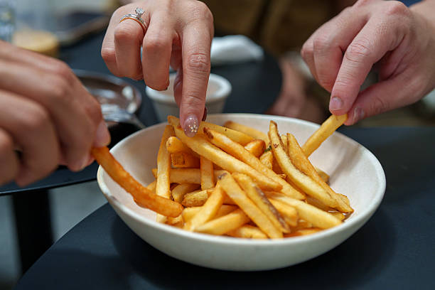 Close Up of People Sharing Crispy French Fries in a White Bowl