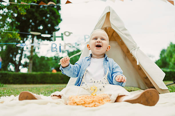 A Joyful First Birthday Celebration featuring a little baby sitting happily inside a tent, surrounded by vibrant party decorations, a delightful cake, and an atmosphere full of laughter and joy