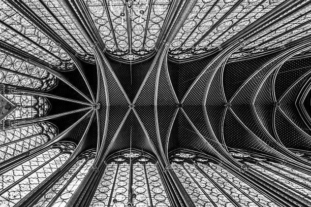 Monumental interior of Sainte-Chapelle with stained glass windows, upper level of royal chapel in the Gothic style. Palais de la Cite, Paris, France. Black and white photography.