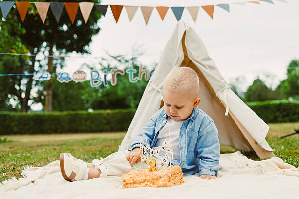 A Delightful and Sweet Birthday Celebration A Joyful Toddler Cheerfully Enjoying a Delicious Cake in a Cozy Outdoor Setting Adorned with Colorful and Festive Decorations for the Special Day