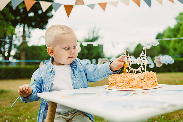 An adorable young child joyfully celebrating their birthday surrounded by cake at a delightful outdoor party filled with colorful decorations, delicious food, festive treats, and smiling friends