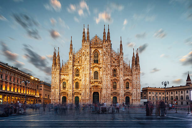 Duomo di Milano at dusk, featuring intricate gothic architecture and blurred crowd movement in Piazza del Duomo