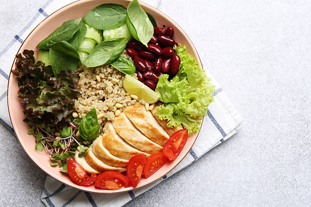 Healthy meal. Tasty vegetables, quinoa and chicken breast in bowl on white table, top view. Space for text