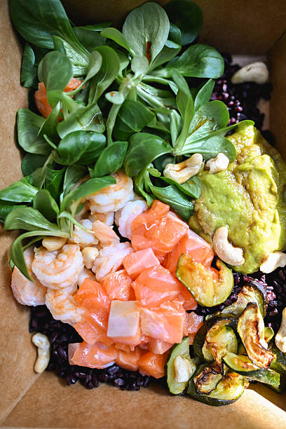 Delicious poke bowl with salmon, shrimp, avocado and black rice