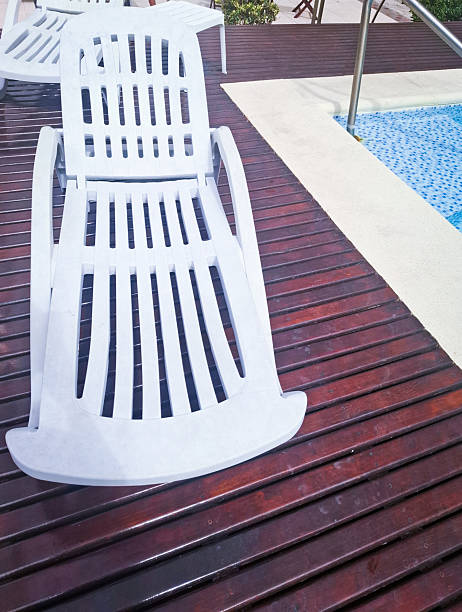Empty sun lounger besides swimming pool
