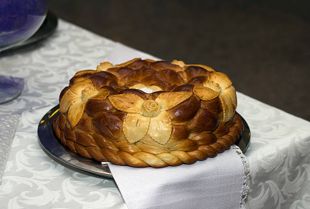 Traditional braided celebration bread, decorated with dough flowers, on a silver platter.