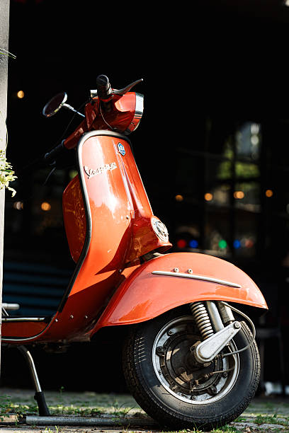 Copenhagen, Denmark, August 9th, 2025, Hot orange classic Vespa scooter parked in the sun during summer day in Copenhagen Denmark.