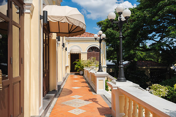 Exterior of a beautifully preserved old colonial building featuring a long balcony with balustrade and decorative lampposts.