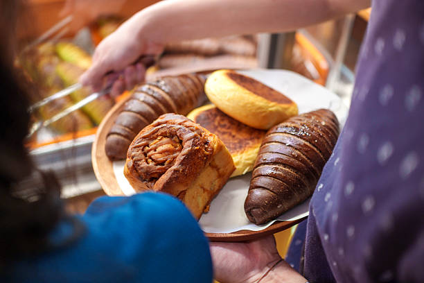 Over the shoulder view of a customer holding a tray of assorted pastries in a bakery
