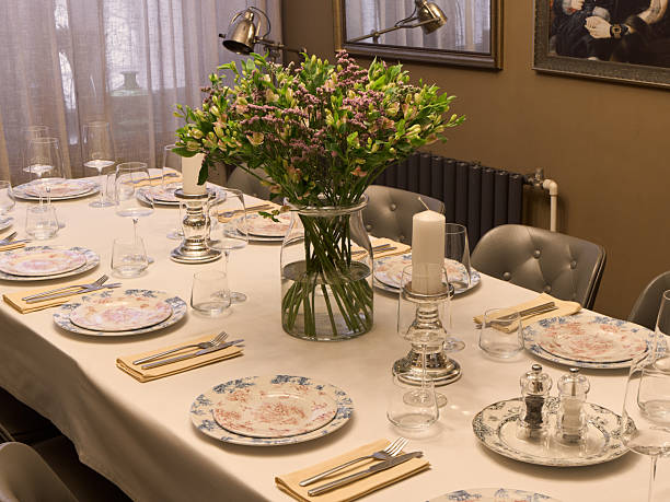 Elegant floral dining table set with glassware china plates polished silverware linen napkins charger plates and large vase filled