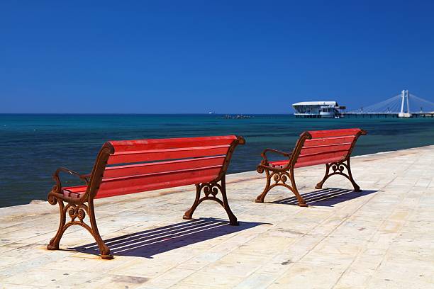 Durres city, Albania. Sea waterfront esplanade with red benches.