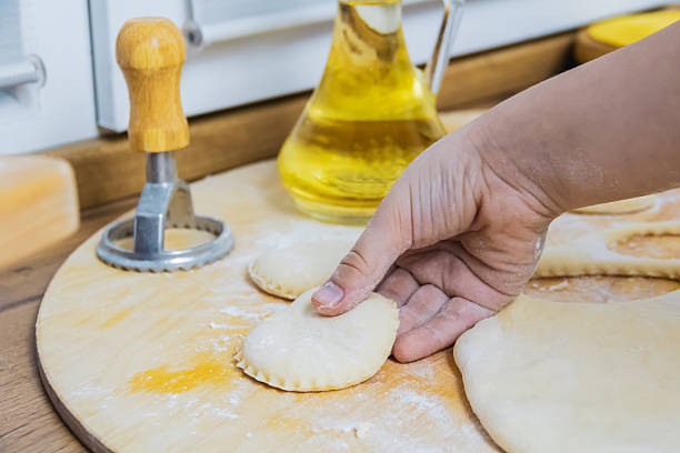 Children's hands make figures out of cookie dough. Making homemade cookies using a mold by hand on a wooden board