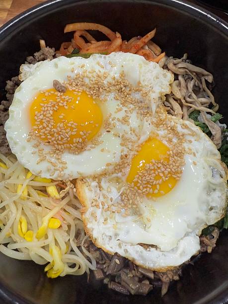 A colorful bowl of bibimbap with steamed rice, fresh vegetables, sliced meat, a fried egg, and a dollop of spicy gochujang. This iconic Korean dish offers a perfect mix of flavors and textures.