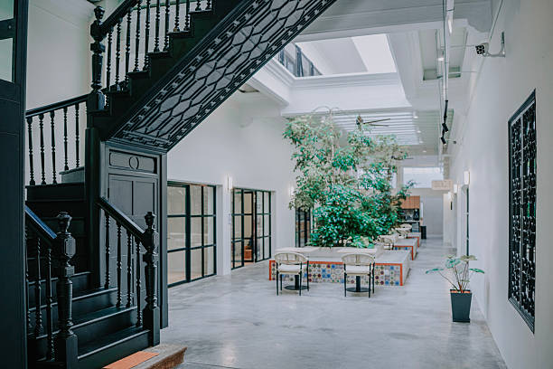 Bright interior courtyard space featuring a dramatic black staircase, white walls, skylight, seating area, and clean architectural design inside a restored heritage style building.