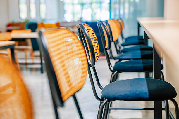 Close-up detail of woven-back chairs arranged along a shared counter in a bright contemporary coworking, café-style, or hospitality interior with a modern relaxed atmosphere, Penang