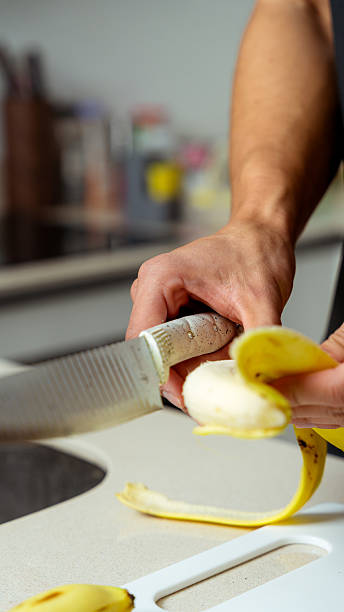 Man's hands peeling banana on cutting board in kitchen