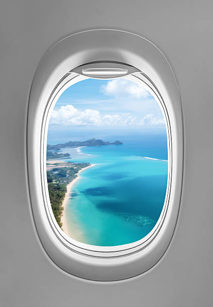 Aerial view of a tropical beach captured from an airplane porthole, showcasing a stunning perspective