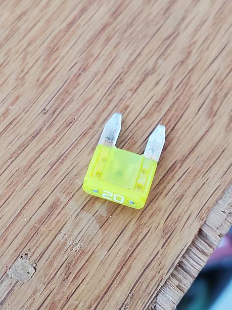 Yellow Twenty Amp Car Fuse on Wood Work Bench Background. High quality photo
