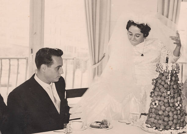 Vintage image from the 1950s : Young couple posing sitting near their wedding cake