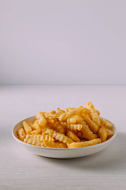 Delicious Golden Crinkle Cut French Fries in White Bowl on Table